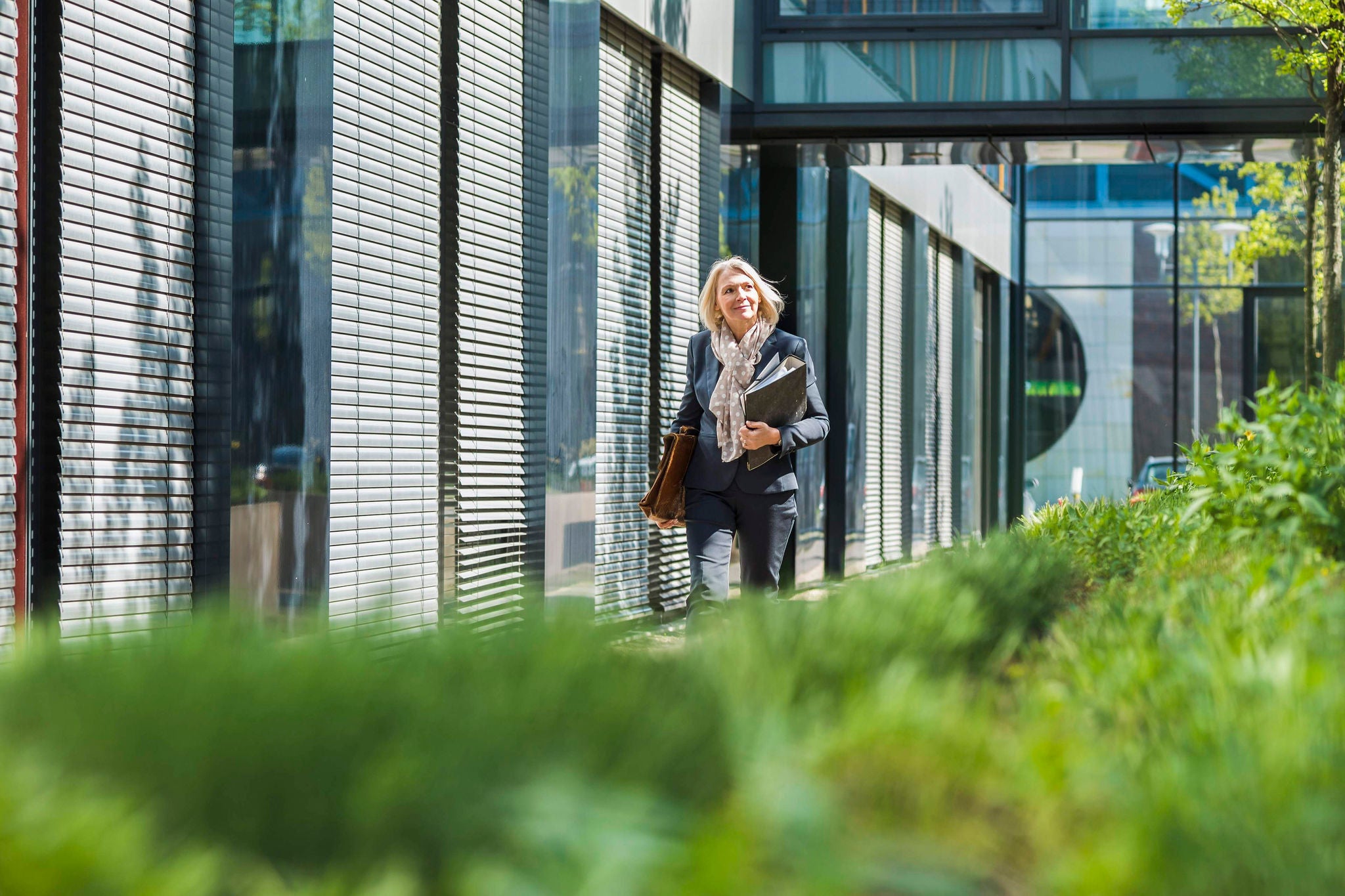 Femme d'affaires portant une mallette et des dossiers devant le bureau