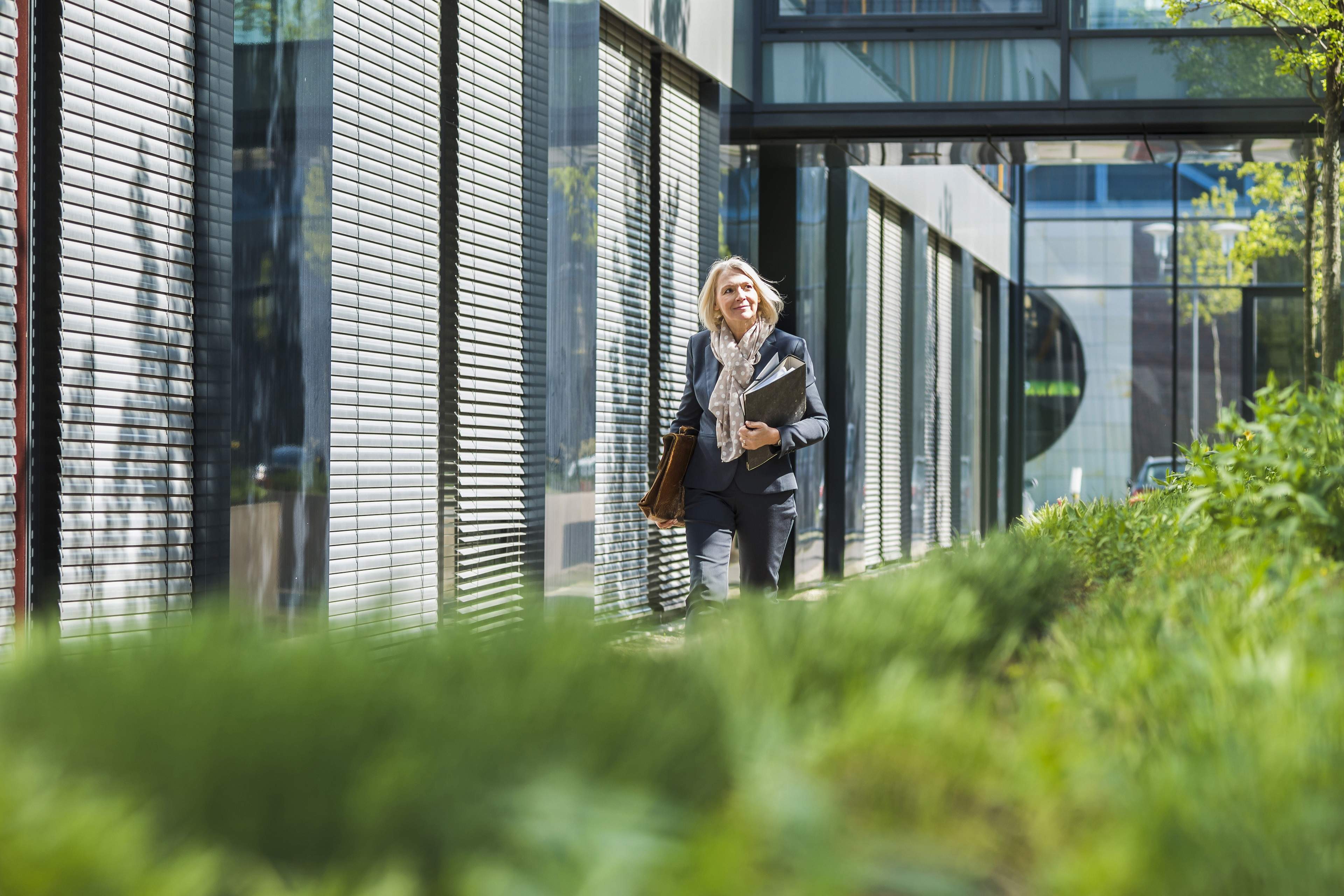 Femme d'affaires portant une mallette et des dossiers devant le bureau