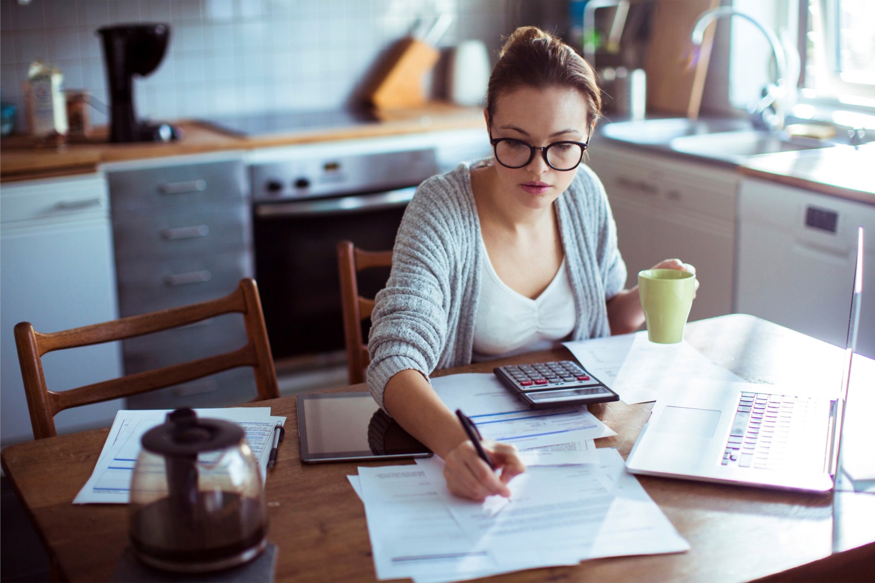 ey young woman doing her bills in herkitchen